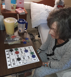 female resident sitting at bedside playing bingo