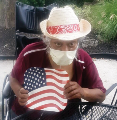 Riverhaven Nursing and Rehab Resident sitting outside holding an American flag for Labor Day Celebration
