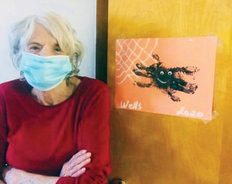 Riverhaven Nursing and Rehab Resident standing in front of her room door with her spider painting