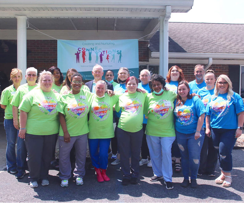 group of adults dressed in green and blue shirts pictured in front of River Haven Nursing and Rehab facility