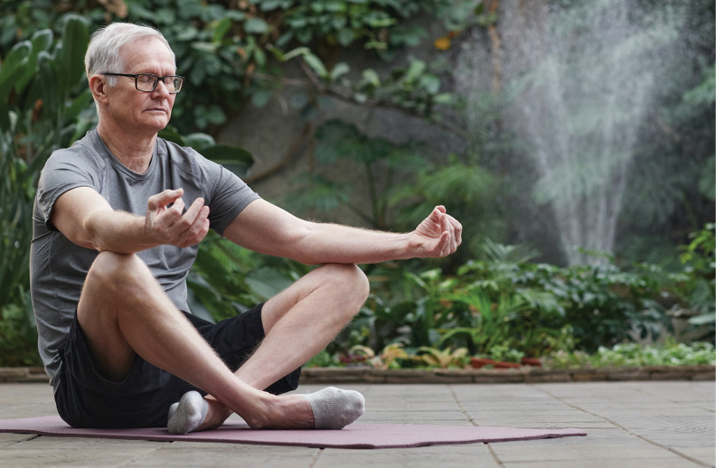 senior man sitting outdoors in meditation stance