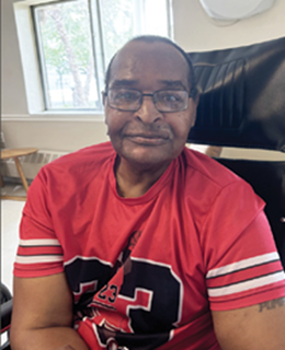 older-adult black man, sitting in chair, smiling for photo. Resident of River Haven Nursing and Rehab