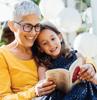 grandmother sitting with granddaughter, reading a book